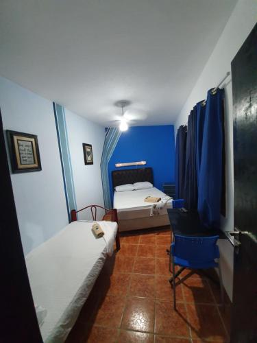 a small room with two beds and a chair at Pousada das Artes 2 in Mongaguá