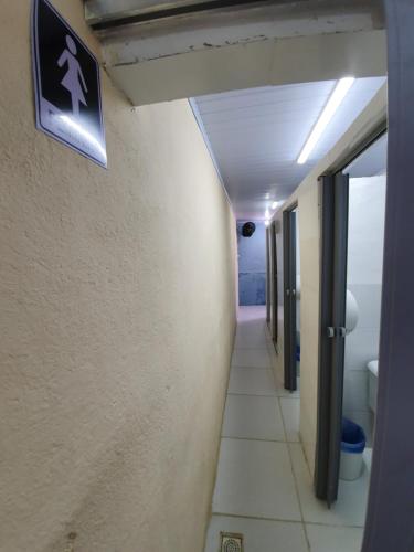 a hallway leading to a bathroom with a sign on the wall at Pousada das Artes 2 in Mongaguá