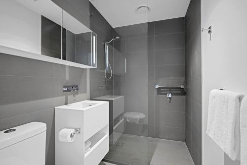 a bathroom with a toilet, sink, and shower stall at Canvas Apartments in Melbourne