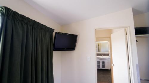 a flat screen tv on the wall of a room at Whangarei Central Holiday Park in Whangarei