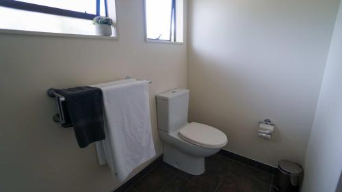 a bathroom with a white toilet and a window at Whangarei Central Holiday Park in Whangarei