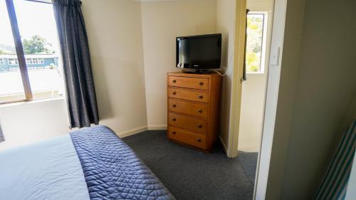 a bedroom with a bed and a television on a dresser at Whangarei Central Holiday Park in Whangarei