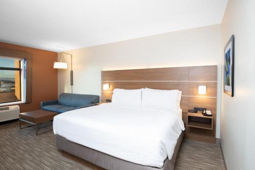 a hotel room with a large bed and a blue chair at Holiday Inn Express & Suites St George North - Zion by IHG in Washington