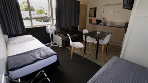 a room with a bed and a table and a kitchen at Whangarei Central Holiday Park in Whangarei