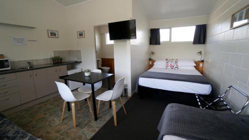 a small room with a bed and a table and chairs at Whangarei Central Holiday Park in Whangarei