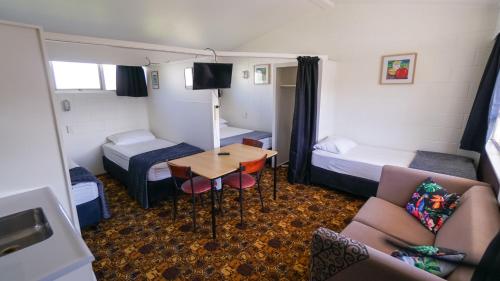 a small room with two beds and a table at Whangarei Central Holiday Park in Whangarei