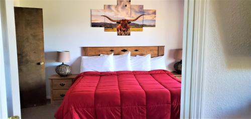a bedroom with a red bed with a bull on the wall at High Sierra Condominiums in Ruidoso
