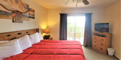 a bedroom with a red bed with a television and a window at High Sierra Condominiums in Ruidoso