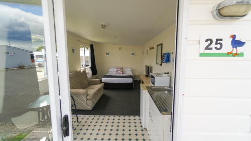 a room with a room with a bed and a couch at Whangarei Central Holiday Park in Whangarei