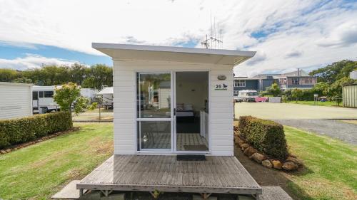 a small white house with a door in a yard at Whangarei Central Holiday Park in Whangarei
