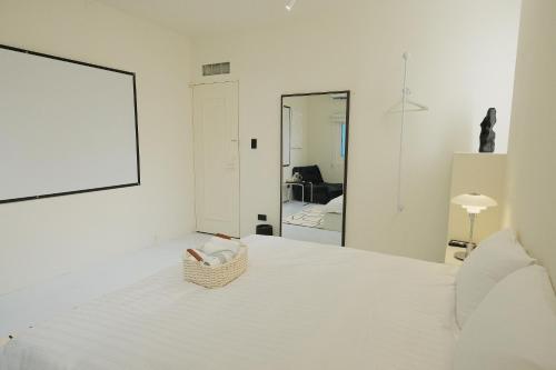 a white bedroom with a bed and a mirror at Bianca in Tainan
