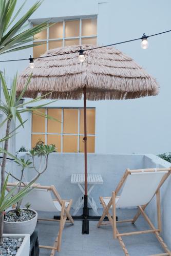a straw umbrella and a chair and a hammock on a patio at Bianca in Tainan