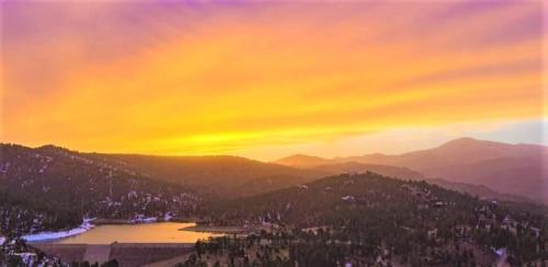 a painting of a sunset with a lake and mountains at High Sierra Condominiums in Ruidoso