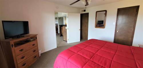 a bedroom with a red bed and a flat screen tv at High Sierra Condominiums in Ruidoso