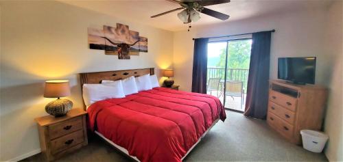 a bedroom with a bed with a red blanket and a tv at High Sierra Condominiums in Ruidoso