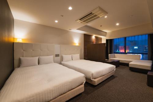 福岡市にあるホテル・ザ・博多テラスのベッド2台とソファが備わるホテルルームです。