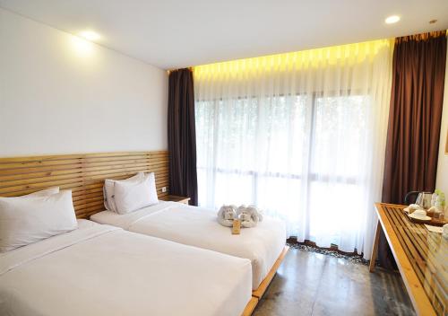 two beds in a hotel room with a window at Greenhost Boutique Hotel Prawirotaman in Yogyakarta