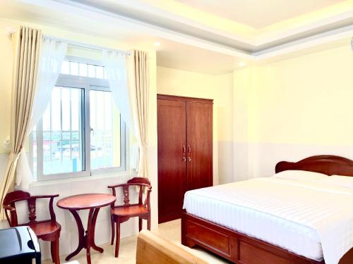 een slaapkamer met een bed en een tafel en stoelen bij Khách sạn Long Hà in Can Tho