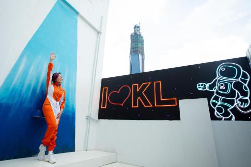 a woman standing on the steps of a building with her arm in the air at Space Hotel @ Chinatown Kuala Lumpur in Kuala Lumpur