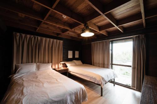 a bedroom with two beds and a window at LOGIN OKINAWA -wood- in Onna