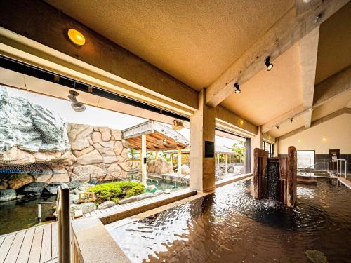 a large room with a pool of water in a building at ジュラシック スパ &リゾート くつろぎの宿 樹楽 in Toon