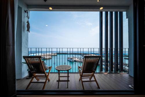 a balcony with two chairs and a table and a view of the water at Marbordo B&B in Xiaoliuqiu