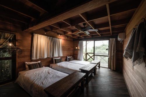 恩納村にあるLOGIN OKINAWA -soil-のベッド2台とベンチが備わる客室です。