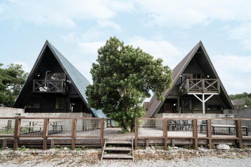 a house with two pointed roofs and a tree at LOGIN OKINAWA -soil- in Onna
