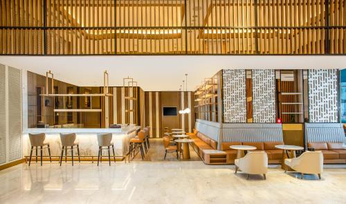 a lobby with tables and chairs and a bar at Swiss-Belhotel Solo in Solo