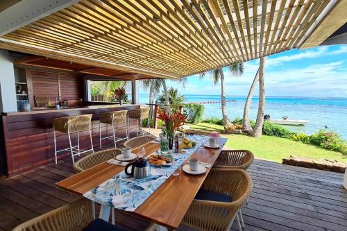 Villa Oona في Maharepa: سطح خشبي مع طاولة وكراسي والمحيط