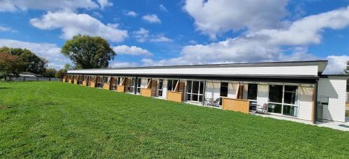 a building with a large field in front of it at Hideaway of Rotorua in Rotorua