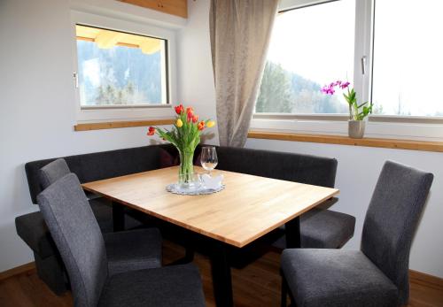 a dining room table with chairs and a vase of flowers at Apart Grubertal in Volders