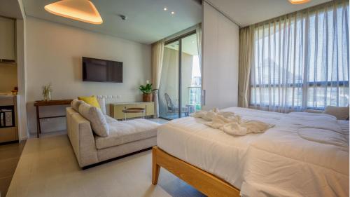 a bedroom with a bed and a couch and a tv at Hua Hin VERANDA BEACHFRONT Living in Hua Hin