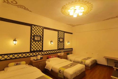 a hotel room with two beds and a chandelier at Gaisang Mêdog Aroma Fragrance Hotel in Lhasa