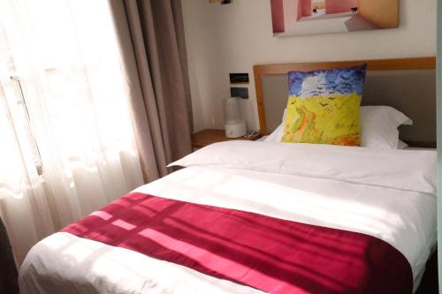 a white bed with a colorful blanket on it at Gaisang Mêdog Aroma Fragrance Hotel in Lhasa