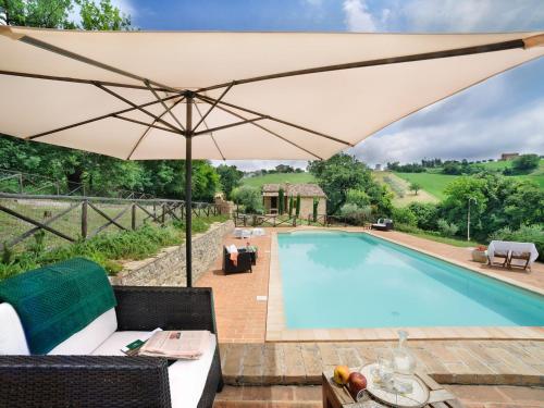 an umbrella over a swimming pool in a yard at Belvilla by OYO Il Rigogolo in SantʼAngelo in Pontano