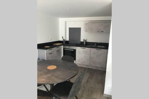 une cuisine avec une table, un évier et une cuisinière dans l'établissement Côté Mer - Maison (3P) au calme proche de la mer, à Barneville-Carteret