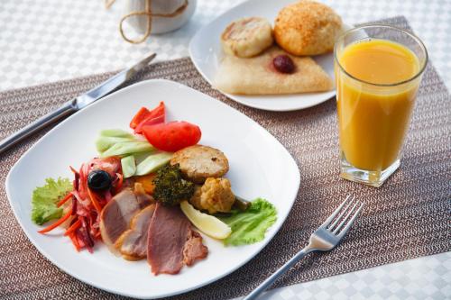 a table with two plates of food and a glass of orange juice at Smart Hotel Bishkek in Bishkek