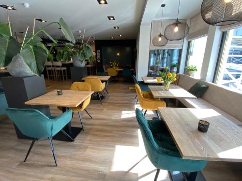 ein Restaurant mit Holztischen, Stühlen und Pflanzen in der Unterkunft Hotel Zee Bergen in Bergen