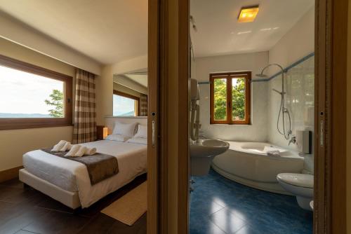 a bedroom with a bed and a tub and a sink at Hotel Ristorante San Carlo in Arona