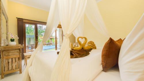 una camera con un letto a baldacchino bianco di Abhirama Villas by Supala ad Ubud