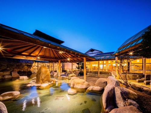 a pool of water with rocks in front of a building at ジュラシック スパ &リゾート くつろぎの宿 樹楽 in Toon