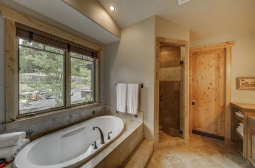 a bathroom with a bath tub and a window at Bear Discovery Custom Tamarack Estate Home by Casago McCall - Donerightmanagement in Donnelly