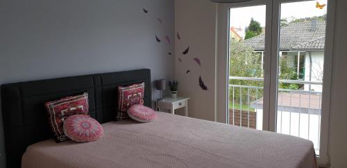 a bedroom with a bed with pink pillows and a window at Ferienwohnung Selina in Losheim
