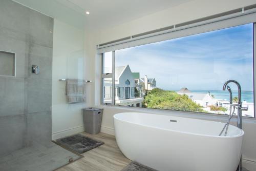 a bath tub in a bathroom with a large window at THE VIEW LANGEBAAN LAGOON VILLA WITH HEATED POOL and SOLAR ENERGY in Langebaan