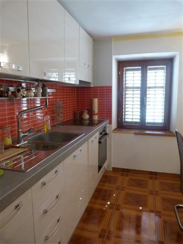 a kitchen with white cabinets and a sink and a window at Apartments Zukanovic in Fažana