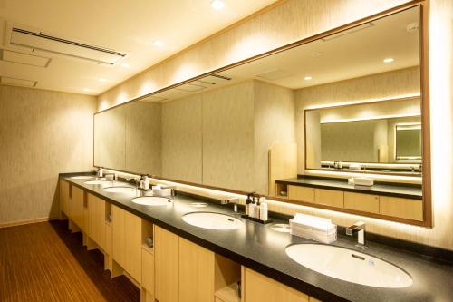 a bathroom with three sinks and a large mirror at Cabin & Capsule Hotel J-SHIP Osaka Namba in Osaka