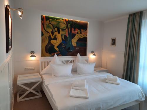 a bedroom with a white bed with a painting on the wall at Beachhotel Cuxhaven in Cuxhaven
