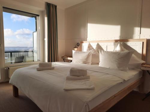 a bedroom with a large white bed with a large window at Beachhotel Cuxhaven in Cuxhaven
