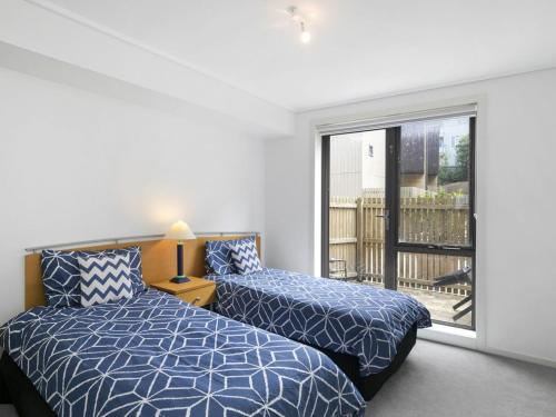 a bedroom with two beds and a large window at Apartment 11 Pacific Apartments in Lorne